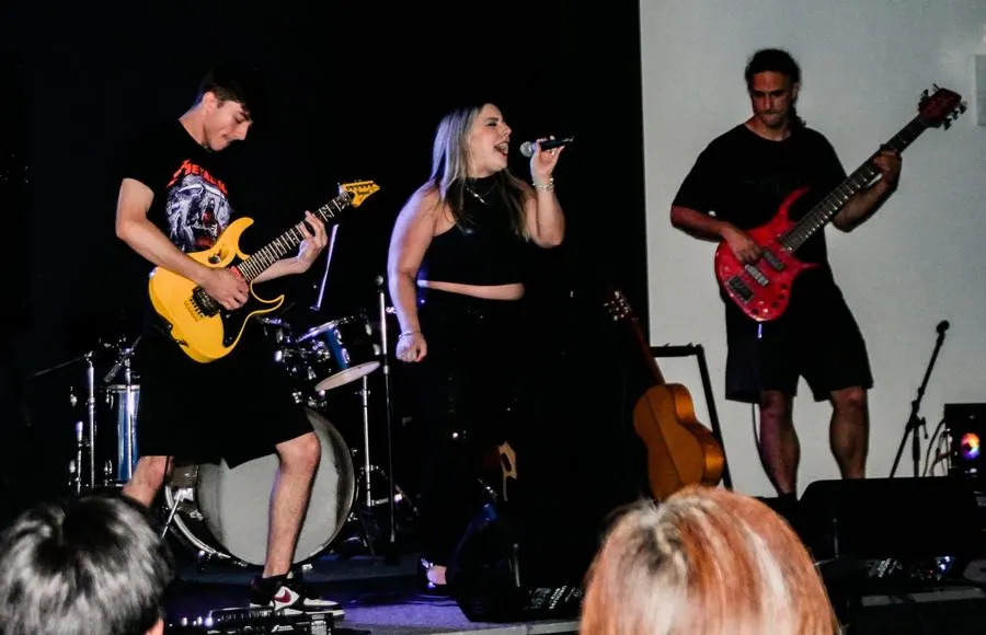 Student band performing guitar, vocals and bass together on stage at a live showcase